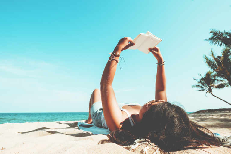 jeune femme sur la plage qui lit un livre